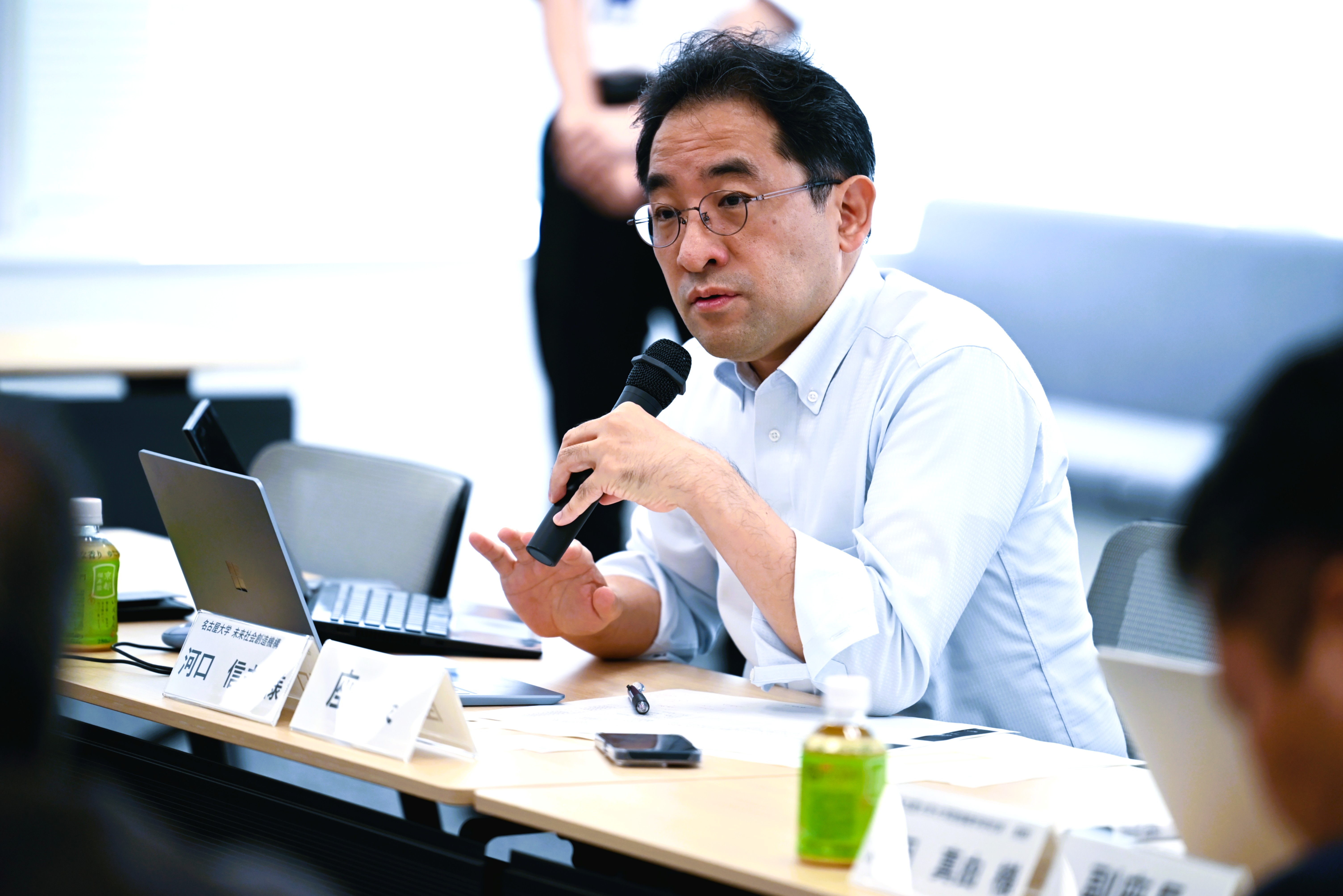 河口教授がマイクを持って話している写真